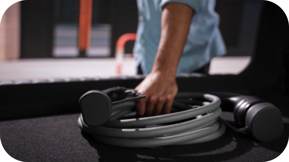A person grabs an electric vehicle charger from their trunk.