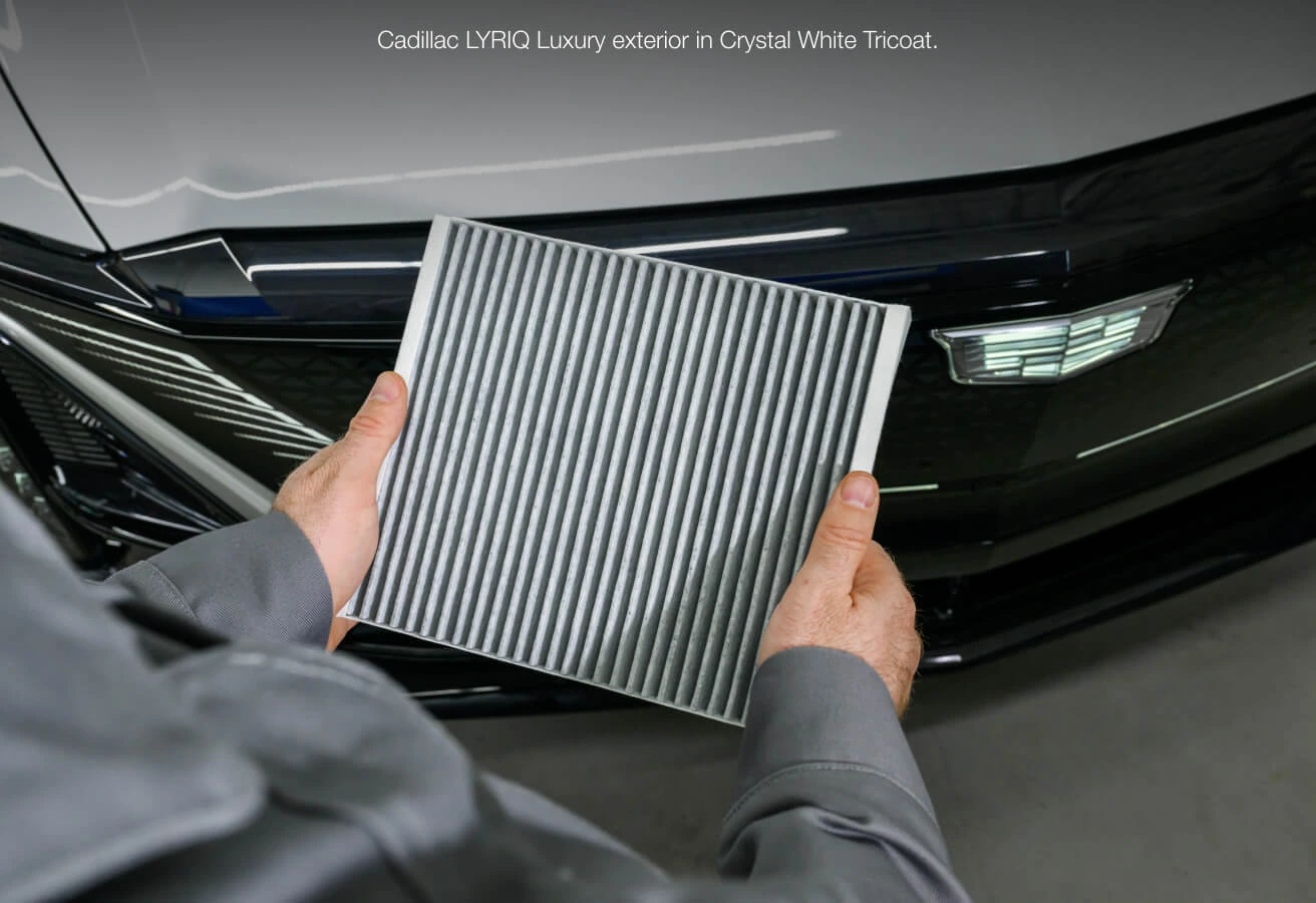 Close-up view of a technician holding a replacement cabin air filter in front of a 2025 Cadillac LYRIQ Luxury fascia.