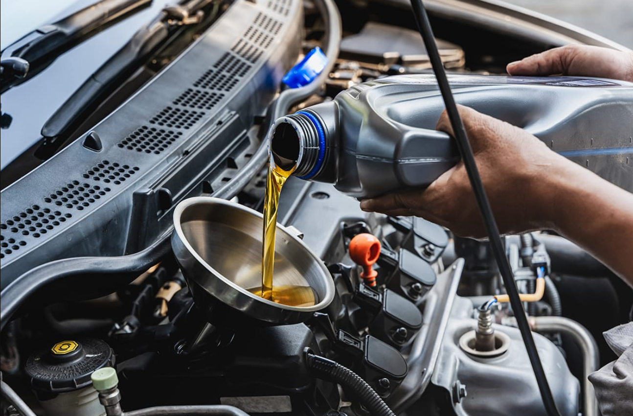 A service tech pours fluid into a car.