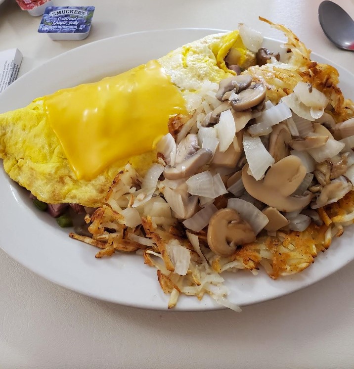 omelette covered with a cheese slice paired with a side of hashbrowns covered in onions and mushrooms