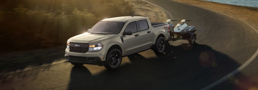 Tan 2024 Ford Maverick Towing Jet Skis on a Coast Road