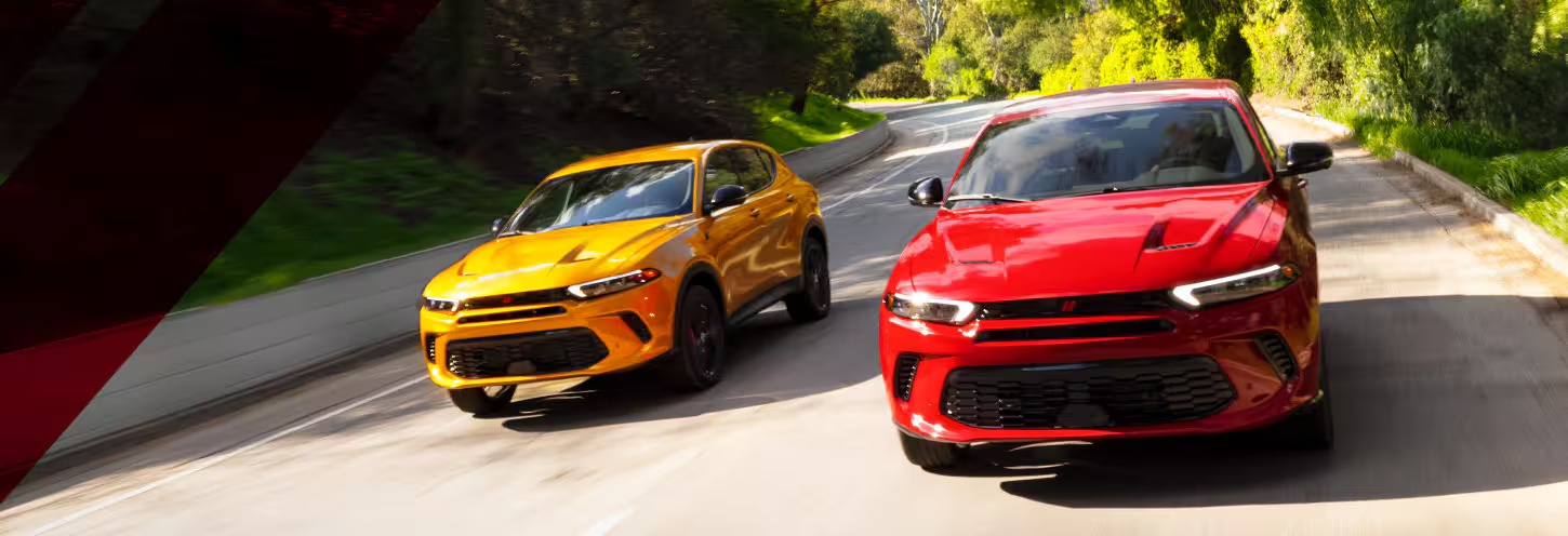 A red and a yellow car driving on the road.