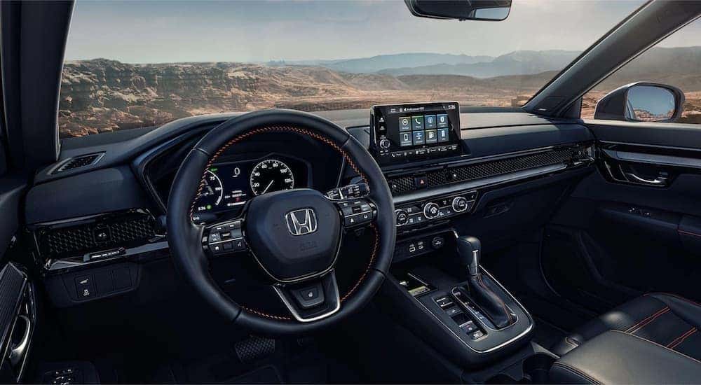 The black interior of a 2024 Honda CR-V is shown from the driver's seat.