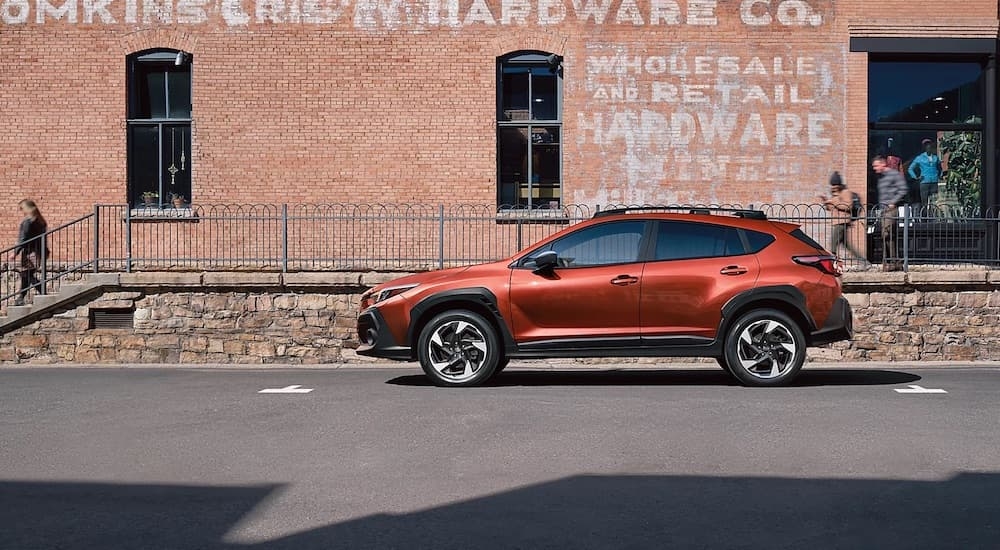 An orange 2024 Subaru Crosstrek Limited for sale in Rhinebeck parked by a building.
