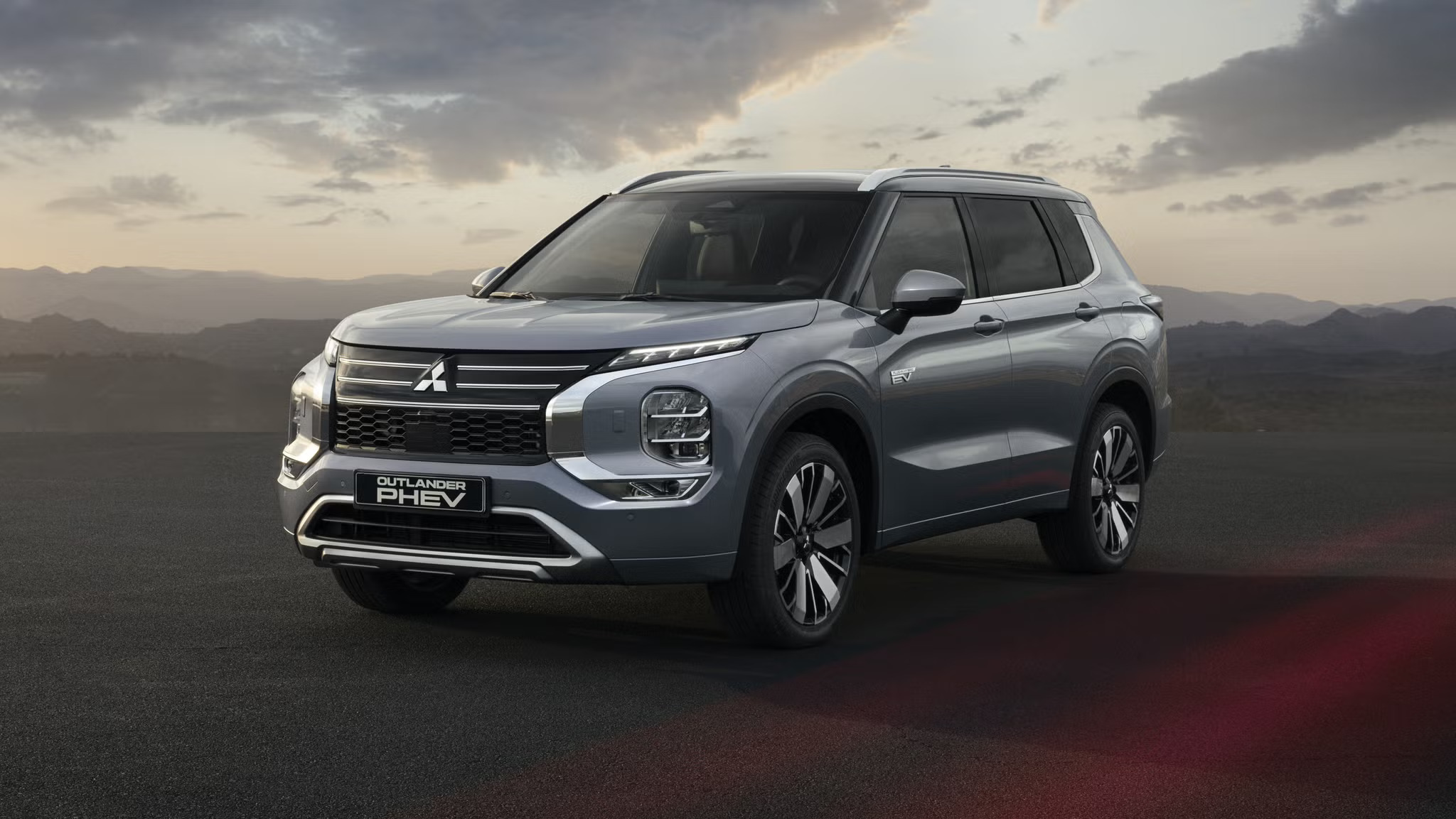 2027 Mitsubishi Outlander PHEV in gray, front three-quarter view at dusk