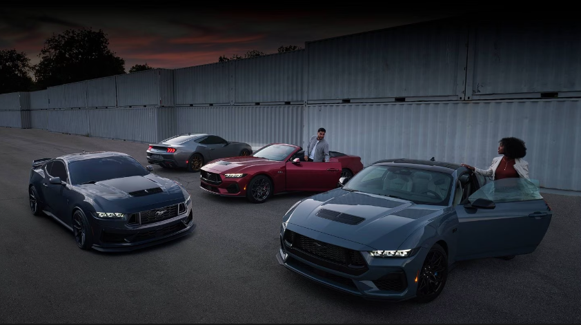 4 ford mustangs parked with two people standing by them