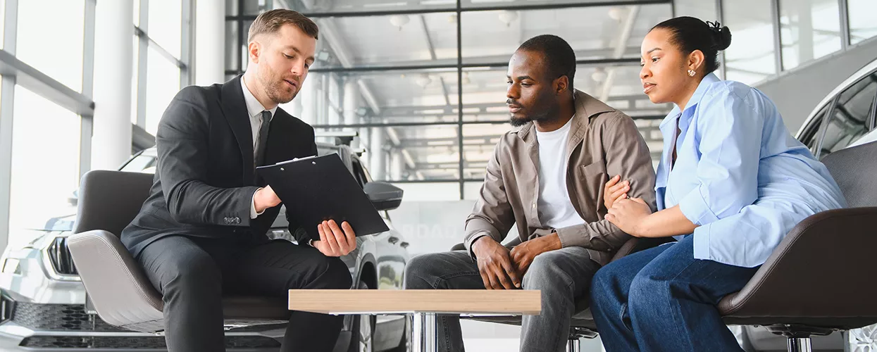 couple speaking with car salesperson at a dealership