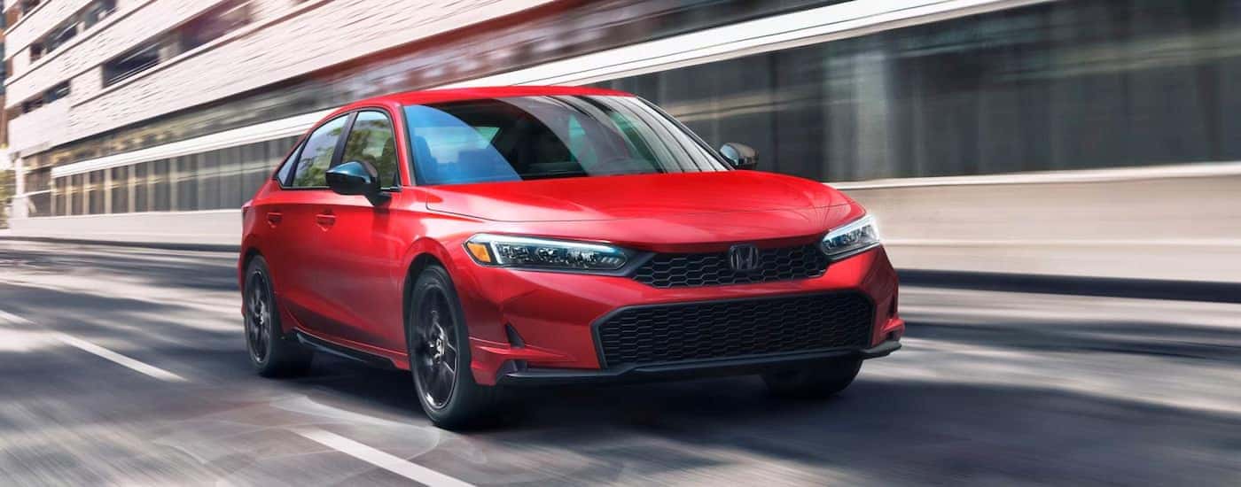 A red 2025 Honda Civic Sport driving on a highway.
