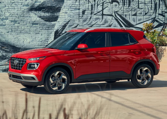 Red 2024 Hyundai Venue parked by a graffiti wall