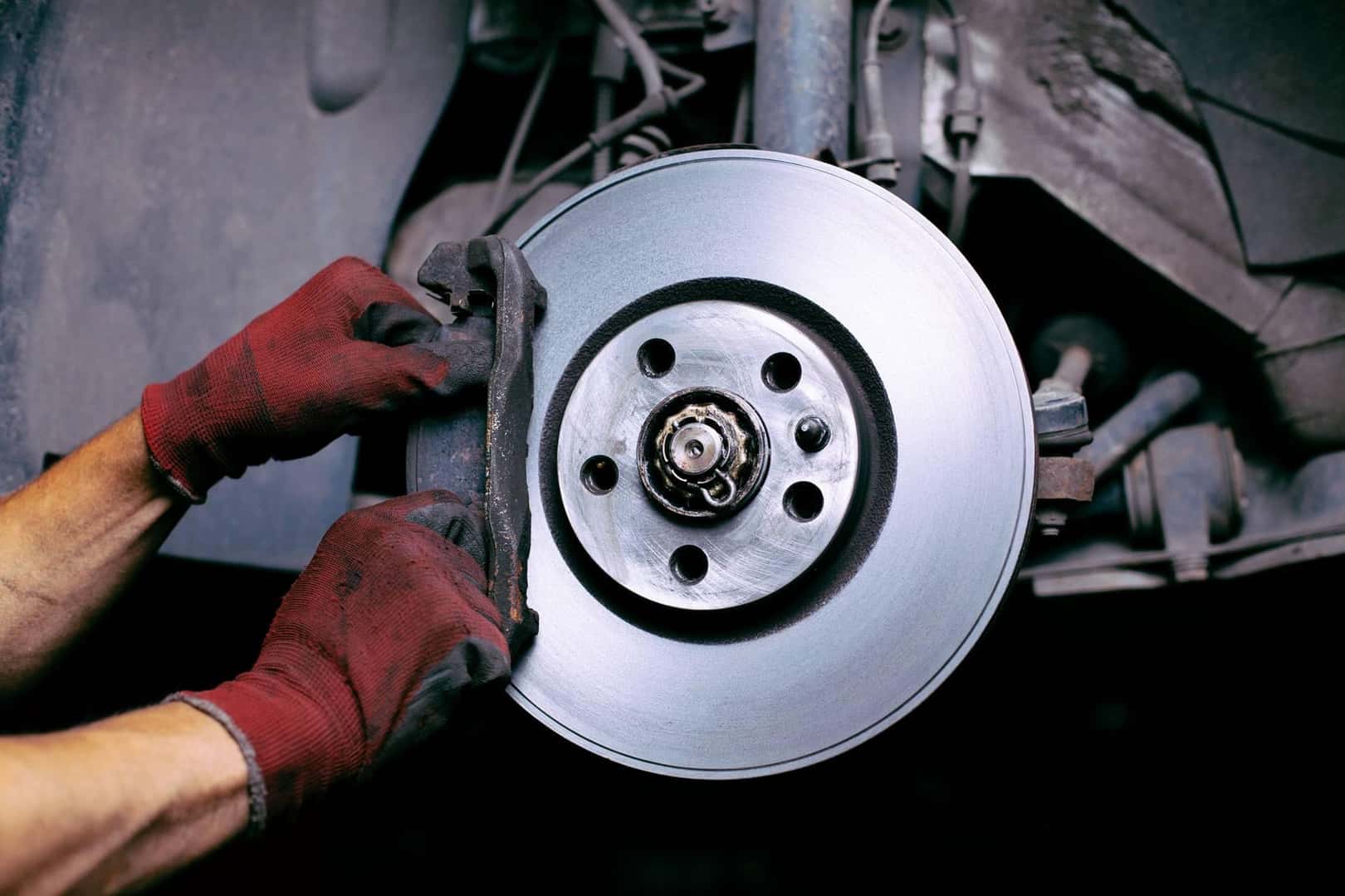 A service technician working on a brake rotor on a luxury vehicle.