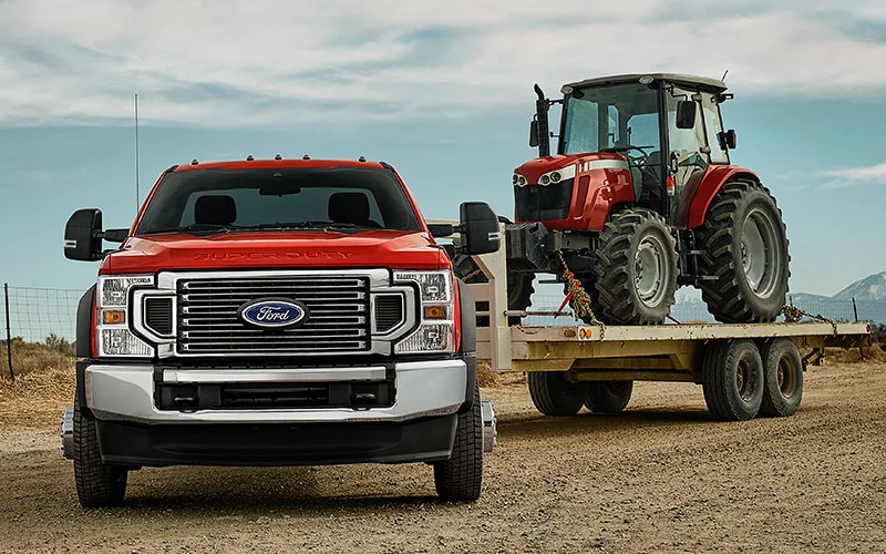 image of red ford truck towing trailer with farm equipment