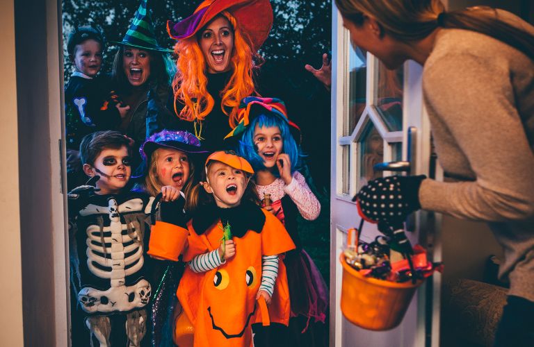 Family in Halloween Costumes Getting Candy at a Door