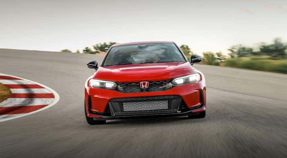 A red 2023 Honda Civic Type R is shown from the front while cornering on a racetrack.