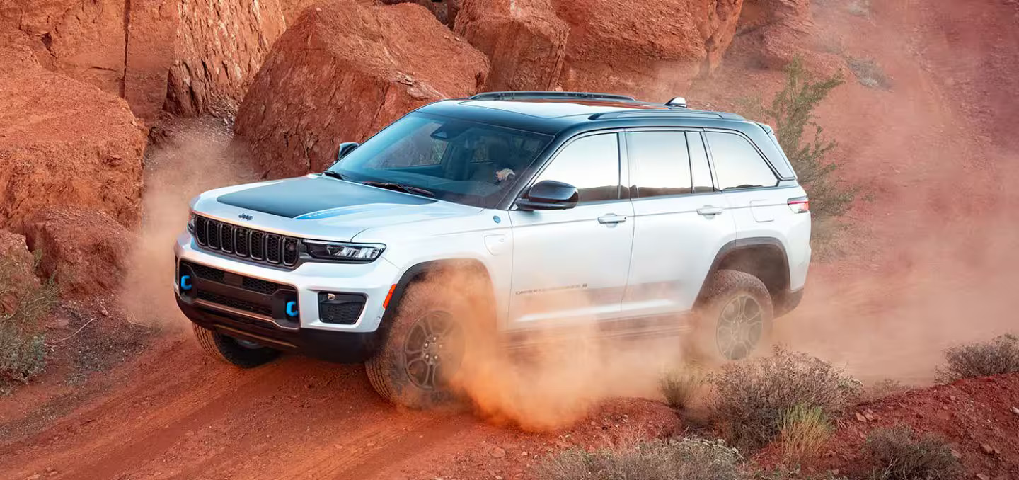 a white car driving over a dirt hill.