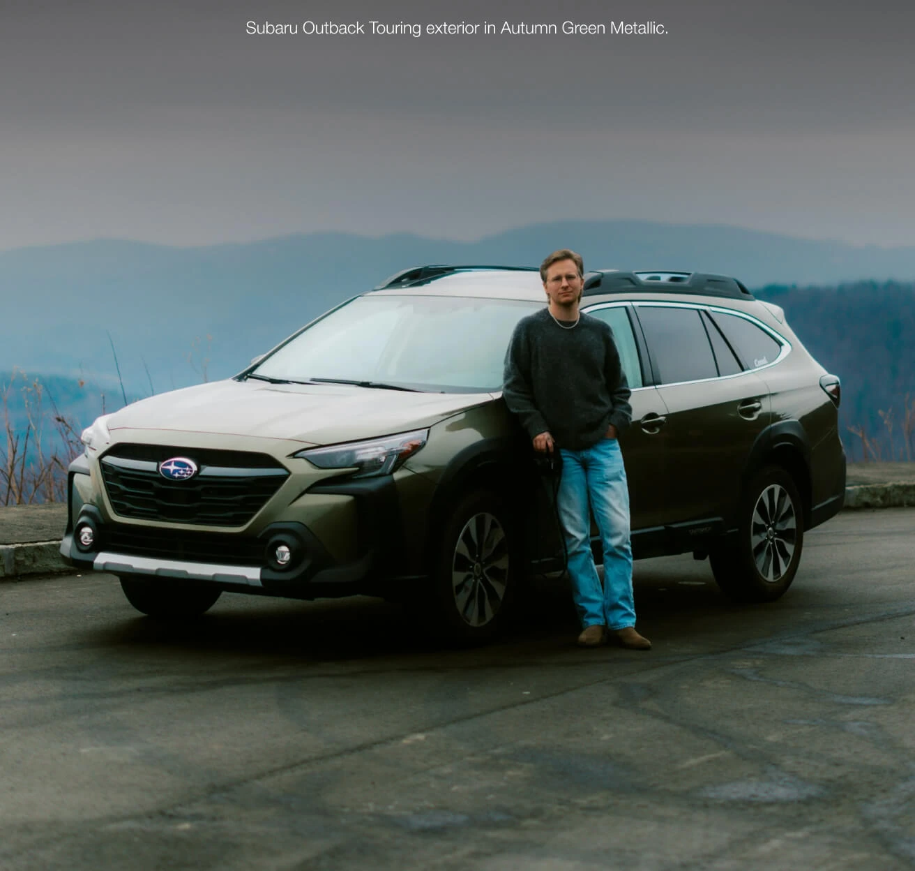 Front three-quarter view 2024 Subaru Outback Touring in Autumn Green Metallic parked at a scenic mountain overlook.