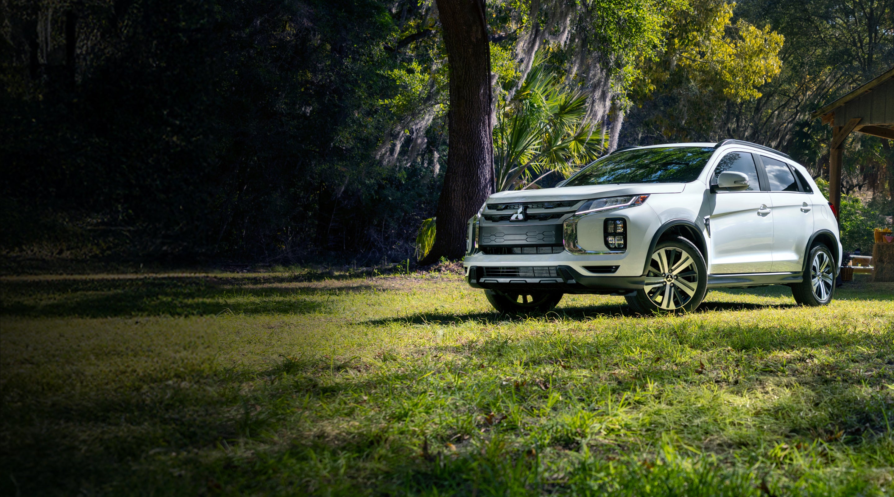2026 silver Mitsubishi Outlander Sport on a dirt patch with tall trees in background