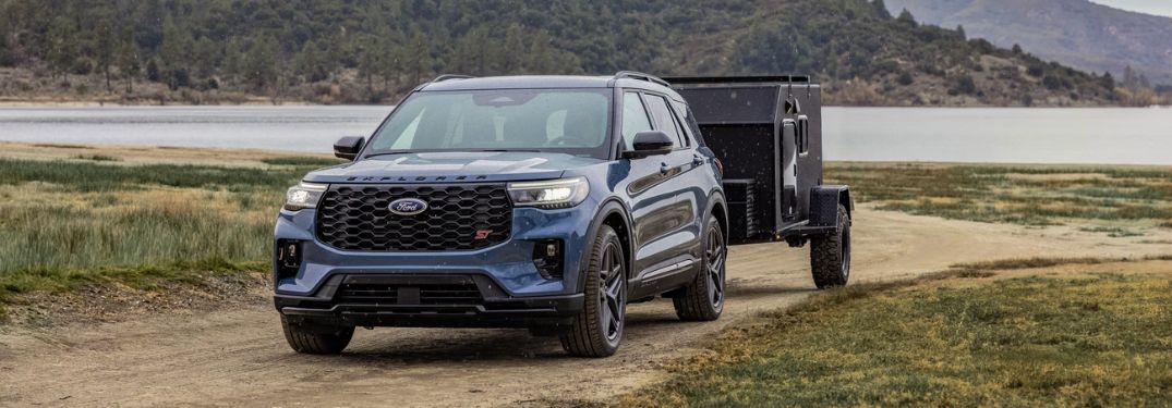 Blue 2025 Ford Explorer ST Towing a Small Trailer by a Lake