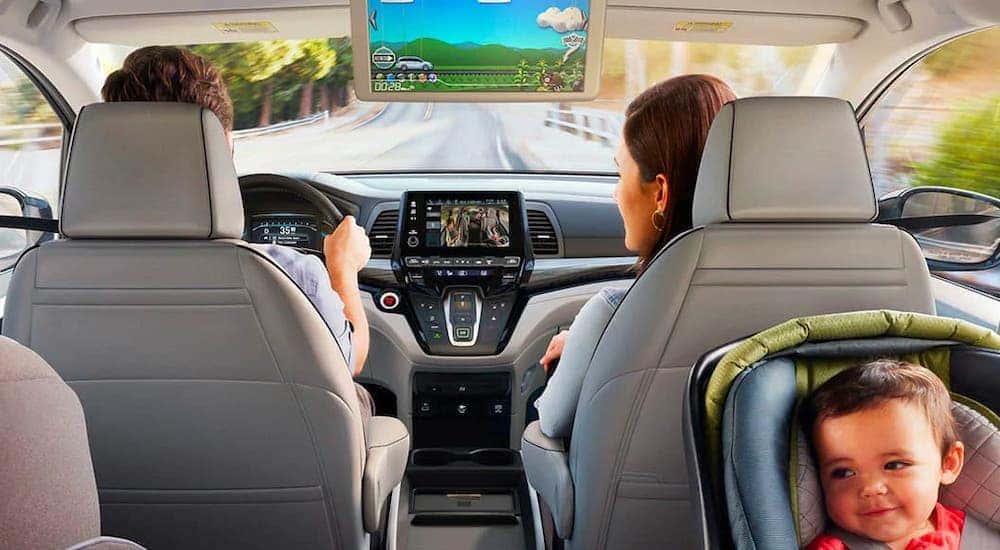 A family is looking at the infotainment screen in a 2020 Honda Odyssey Elite.