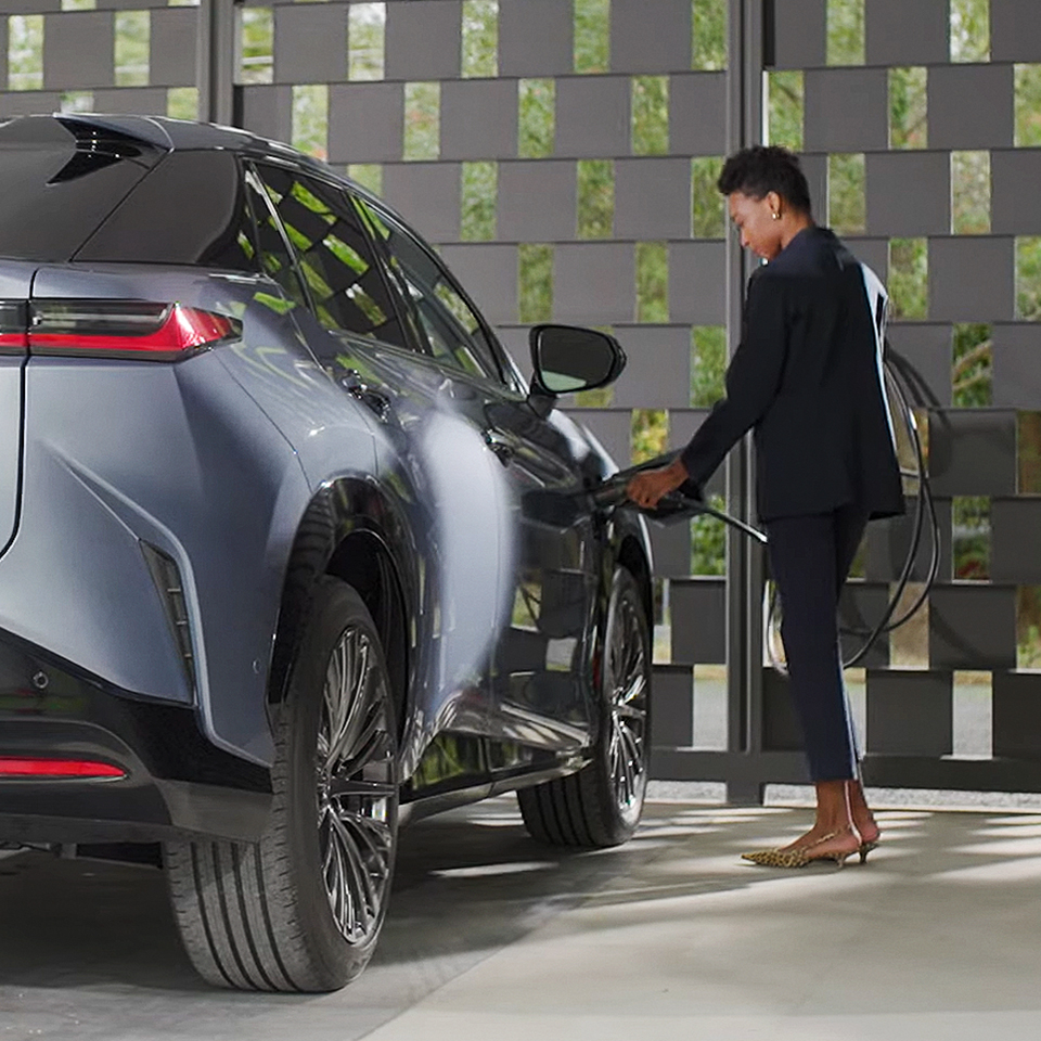 A person plugs a charger into their vehicle's charging port. 