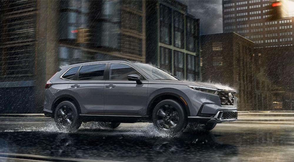 A gray 2026 Honda CR-V driving on a wet city street.