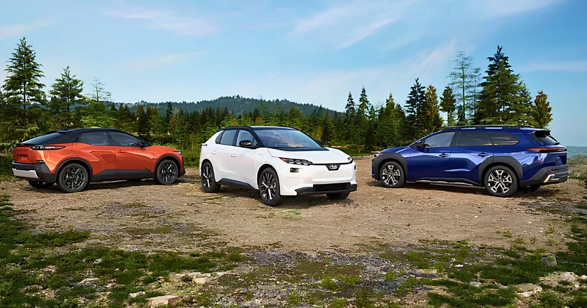 Three Subaru electric SUVs in orange, white and blue parked in a forest clearing