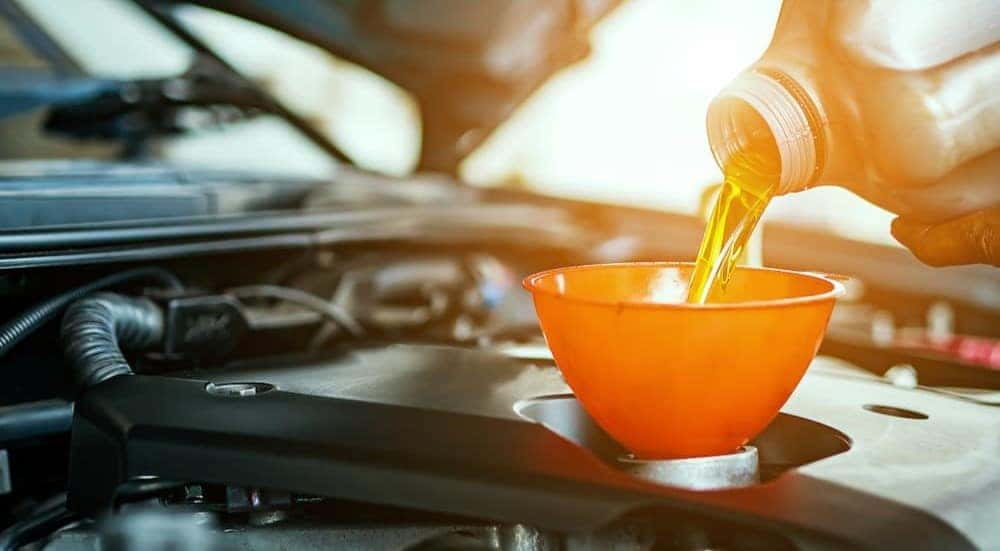 A mechanic is shown pouring oil while performing an oil change near Henrietta.
