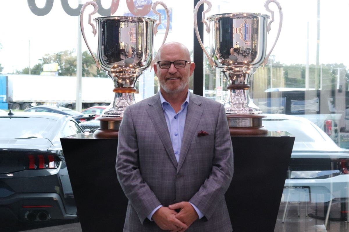 Brandon Ford General Manager in Front of Trophies in Dealership Showroom