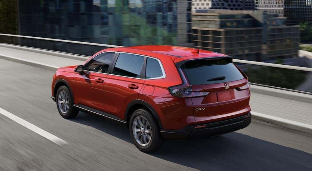A red 2023 Honda CR-V EX shown driving on a highway after visiting Ralph Honda, a Honda CR-V dealer.