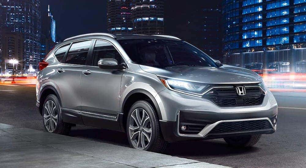 A silver 2020 Honda CR-V Touring from a local Honda dealer is parked on a city street at night.