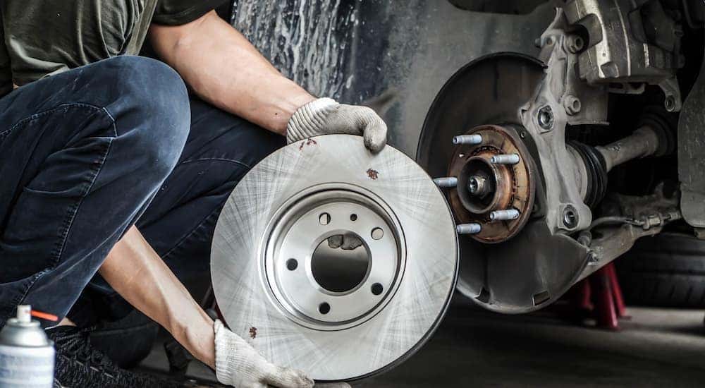A mechanic is holding the rotor of a vehicle.