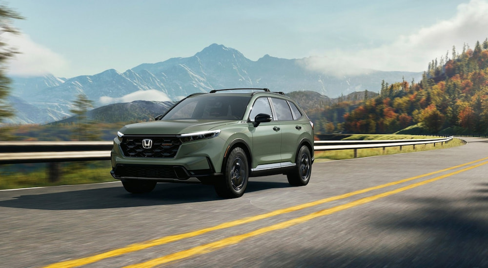 Green 2026 Honda CR-V driving down an open road.