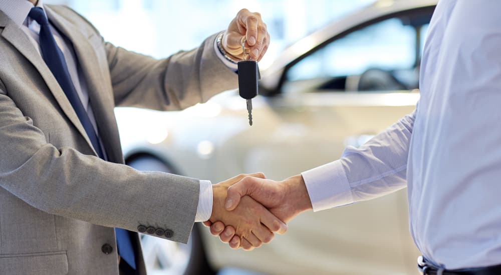 People shaking hands and swapping car keys.