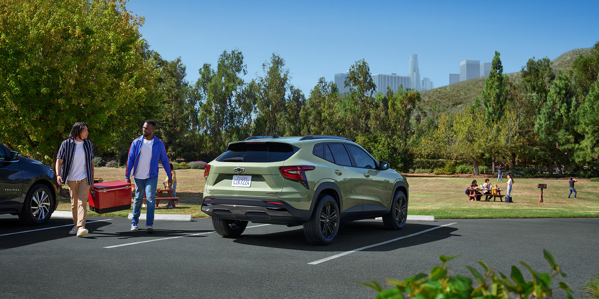 a green chevrolet trax parked at a park with people having picnics
