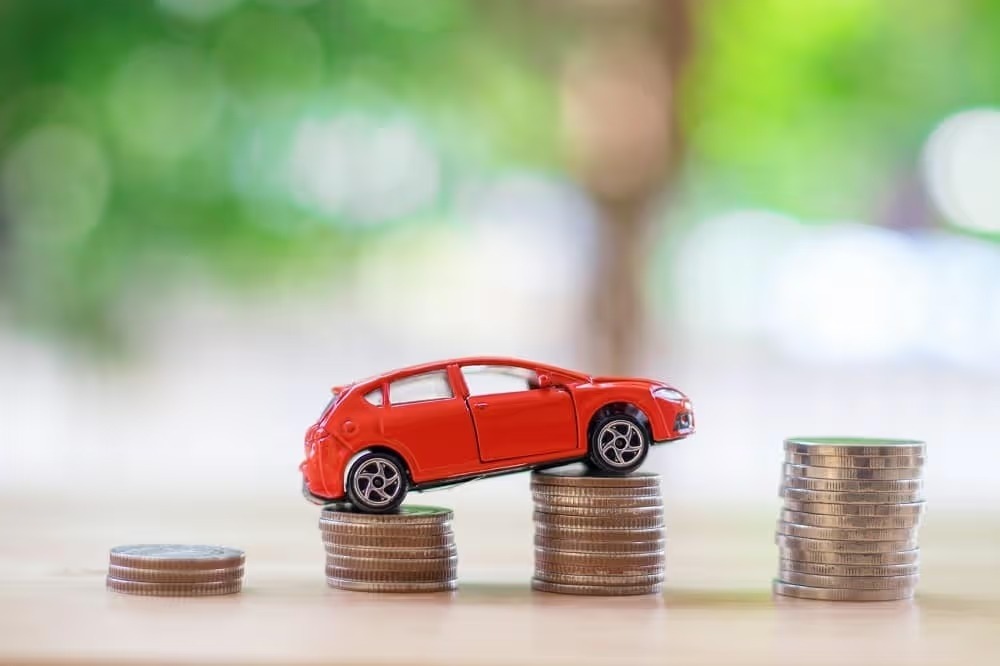 Red toy car sitting on stacks of coins
