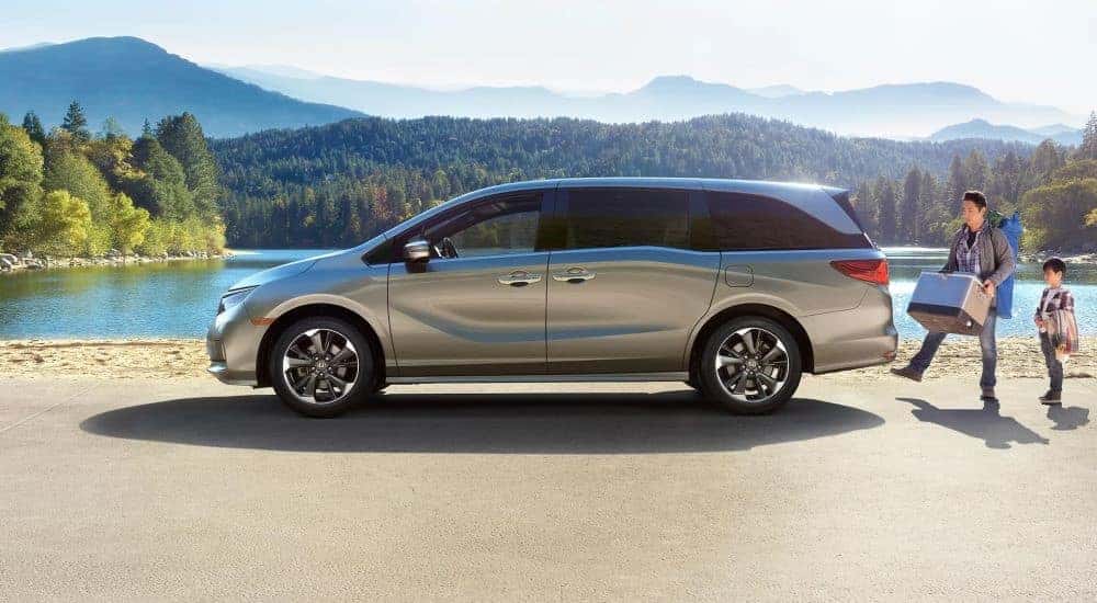 A person is shown loading a cooler into a silver 2023 Honda Odyssey.