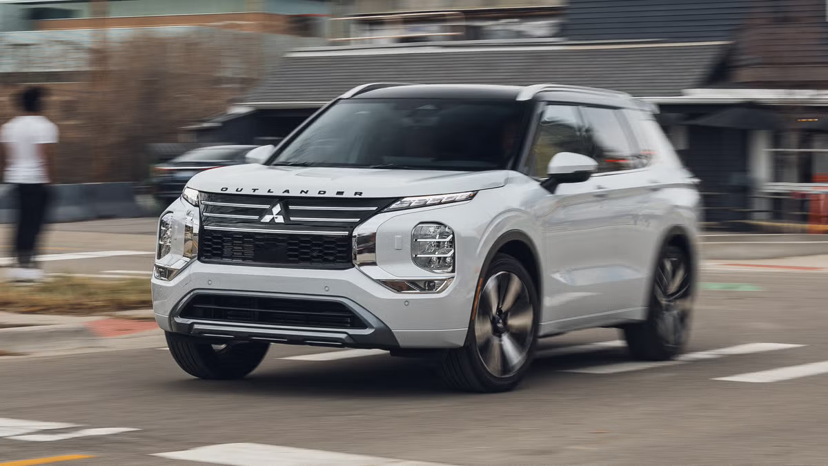 2027 Mitsubishi Outlander PHEV in white driving on a city street, front three-quarter view