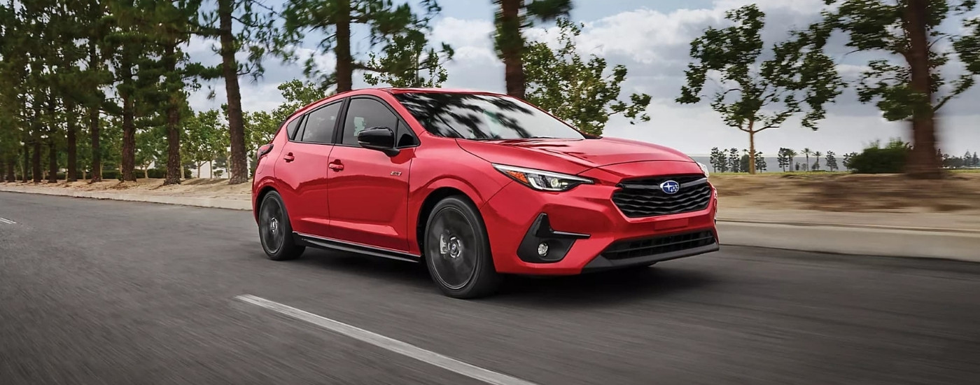 Red 2024 Subaru Impreza RS driving to a Subaru dealer