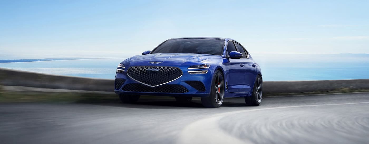 Blue 2026 Genesis G70 driving around a bend.