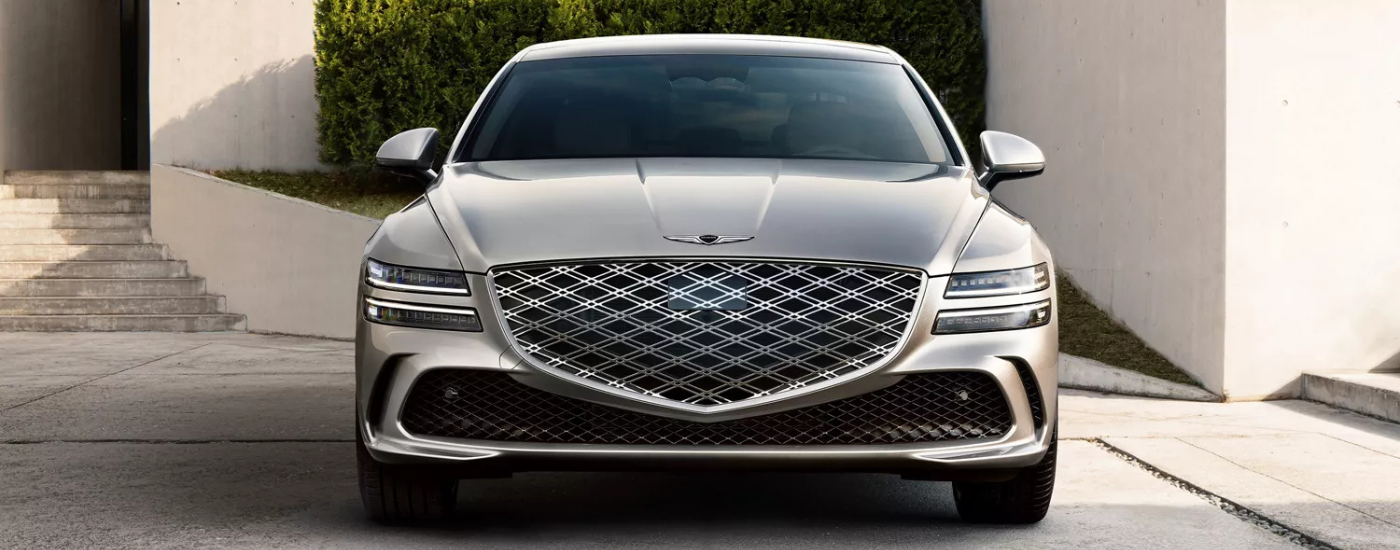 Silver 2025 Genesis G80 head on in front of a house