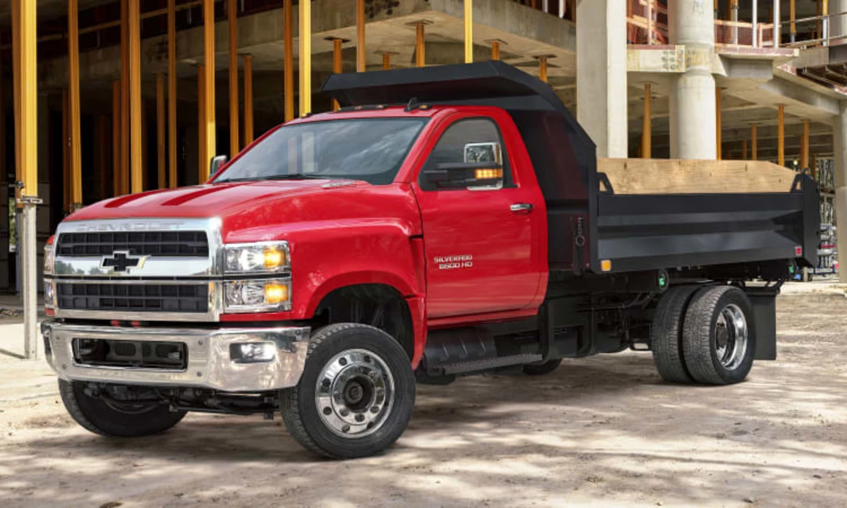 A red Chevrolet Silverado 6500 commercial truck with a black dumper bed providing it's services at a commercial construction site.