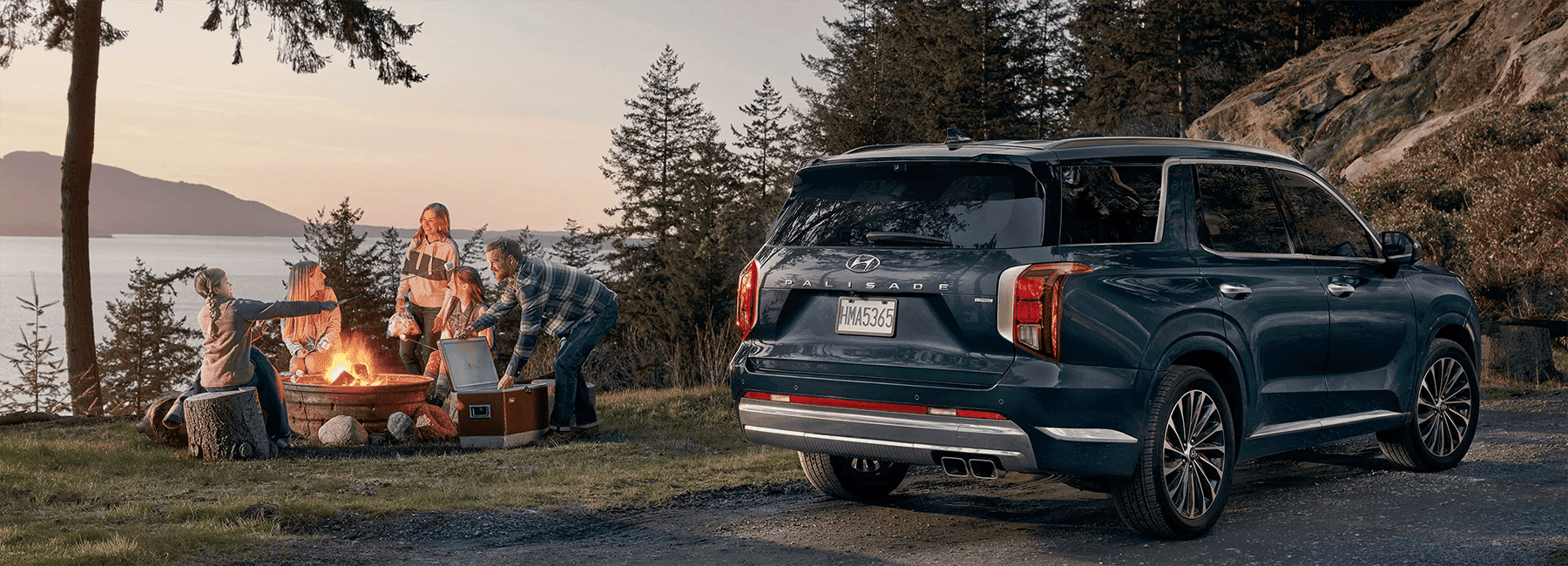 Blue Hyundai Palisade parked beside a family gathered around a campfire