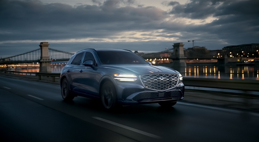 Grey 2026 Genesis GV70 for sale driving past a bridge