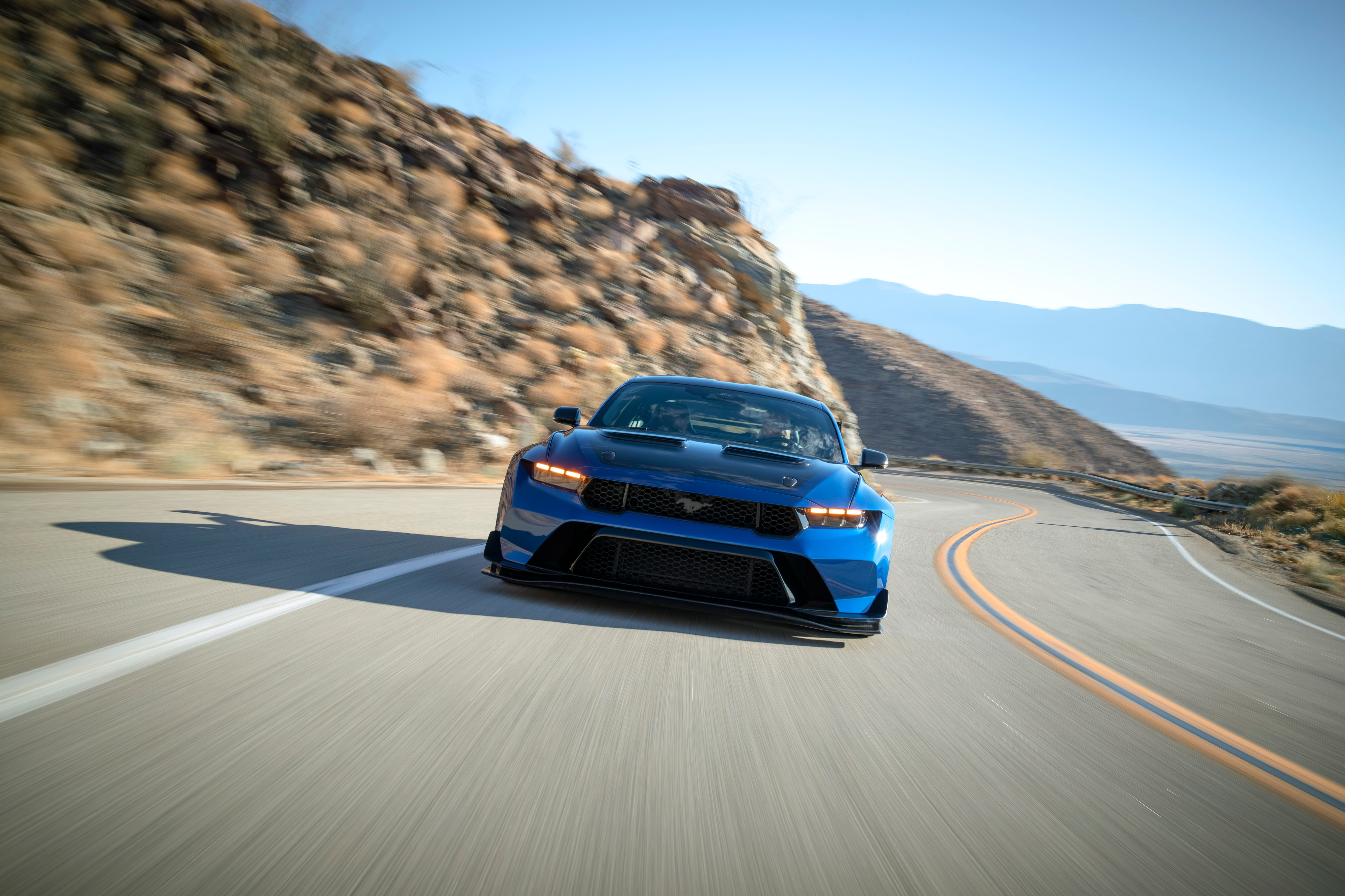2027 Ford Mustang GTD in blue driving on a mountain road, head-on front view