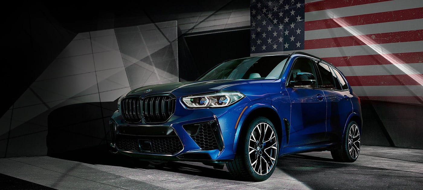 BMW X5 M with Competition Package parked with an American flag in the background