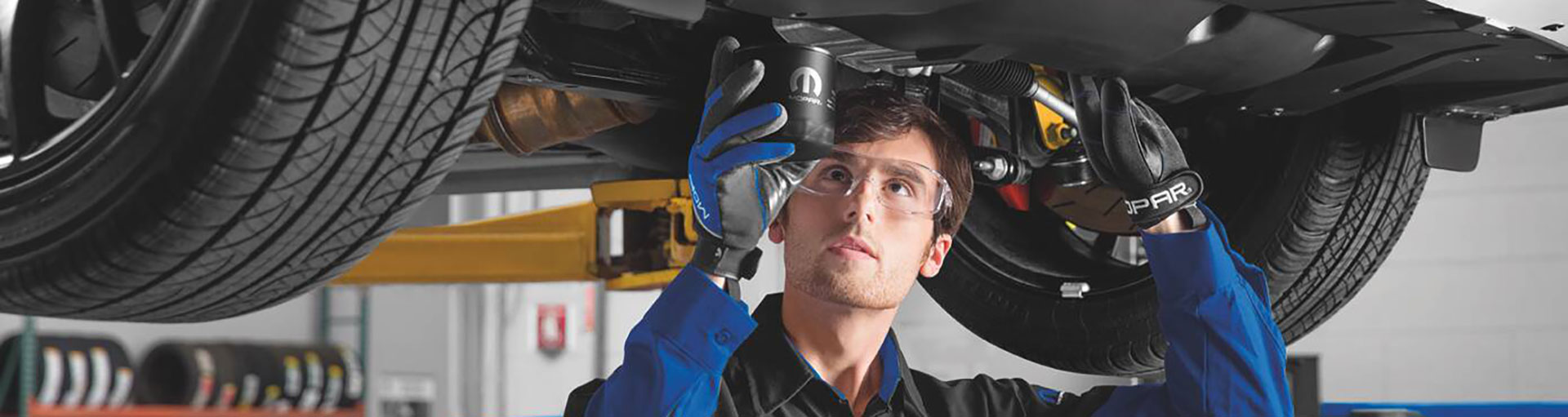 Technician inspecting the underside of a vehicle on a lift