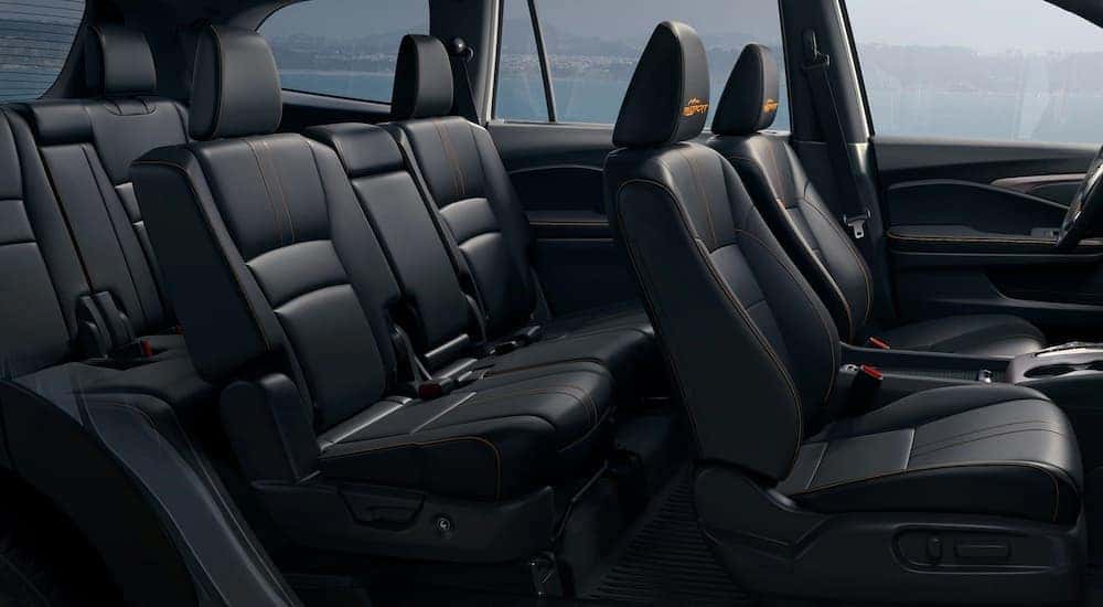 Black leather interior of a 2022 Honda Pilot Trailsport shows three rows of seating.