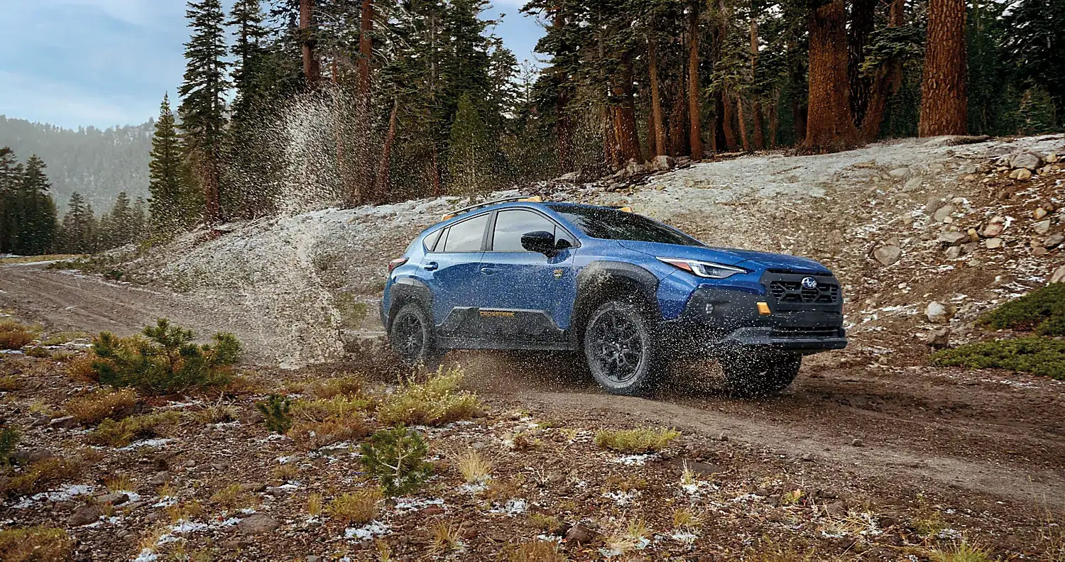 Blue Subaru Crosstrek Wilderness splashing through a muddy trail