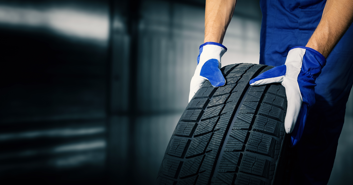 A man wearing gloves rolls a tire