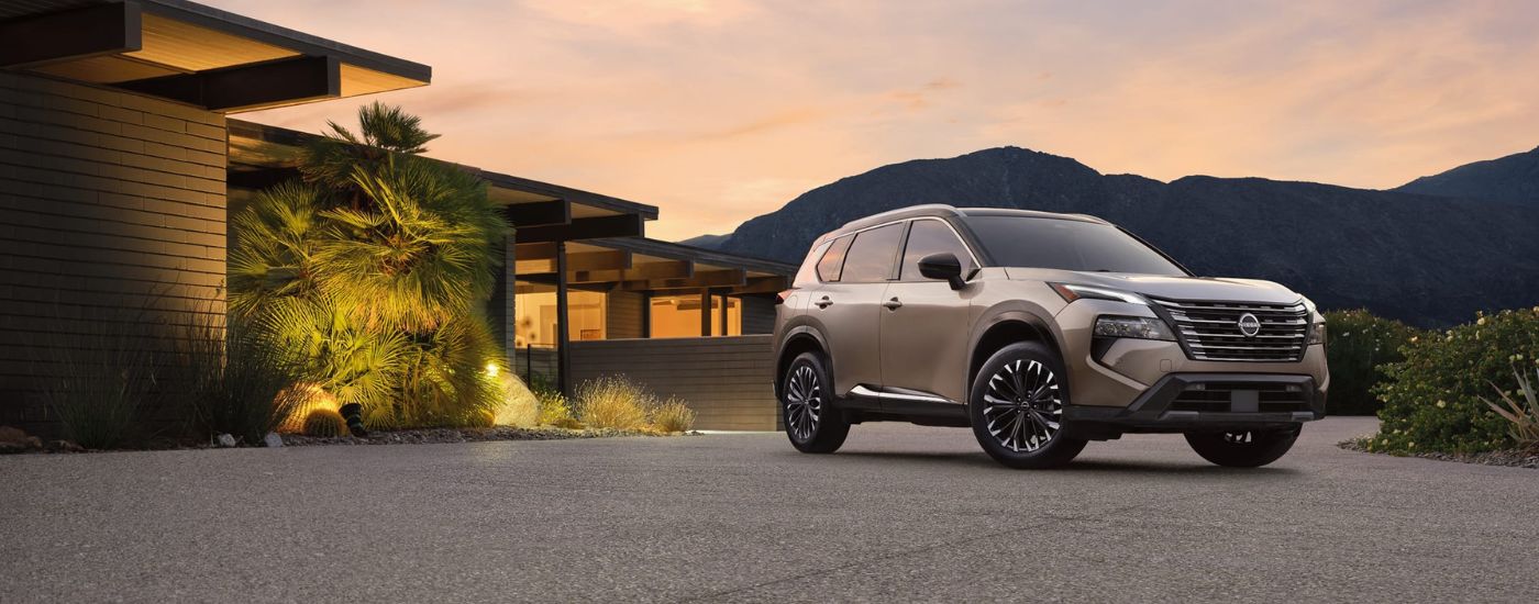 Tan 2026 Nissan Rogue parked in the driveway of a modern home.