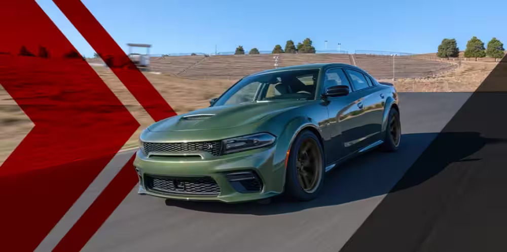 A green dodge charger driving on a road.